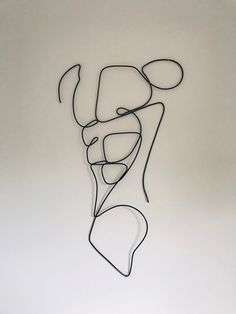 a metal sculpture on a white wall with black lines in the shape of a woman's head