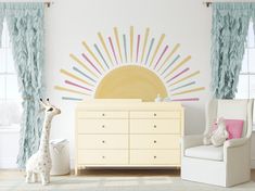 a baby's room with a sun wall decal on the wall and a toy giraffe next to it