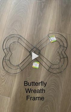 the butterfly wire frame is sitting on top of wood flooring and has tags attached to it