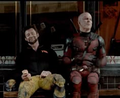 two men sitting next to each other in front of a store window with deadpools on the windowsill