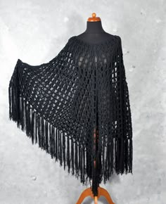 a black crocheted shawl with fringes on a mannequin stand