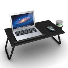 an open laptop computer sitting on top of a table next to a cell phone and coffee cup