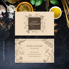 two business cards sitting on top of a table next to some spices and herbs,