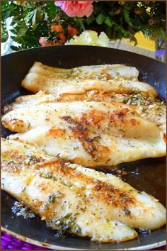 two pieces of fish are cooking in a frying pan with herbs and seasonings