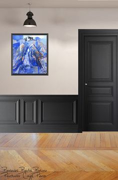 an empty room with wooden floors and black doors in the center, there is a painting hanging on the wall