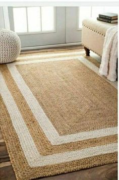 a rug with white and beige stripes on the floor in front of a window next to a bed