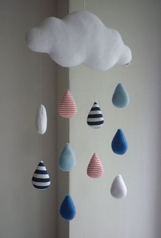 a mobile made out of clouds and raindrops hangs from the ceiling in front of a window