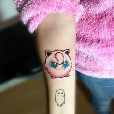 a person with a cat tattoo on their arm and behind her is a pink teddy bear