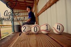 a man sitting on top of a wooden bench next to three baseballs in front of him