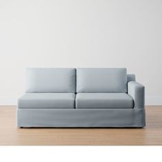 a light blue couch sitting on top of a wooden floor next to a white wall