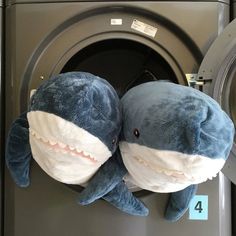 two stuffed sharks sitting on top of a dryer in front of a washing machine