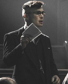 a man wearing glasses holding a piece of paper in his hand