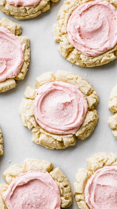 cookies with pink frosting are arranged on a baking sheet