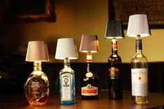 there are many different types of liquor on the table with one light turned on and two empty bottles sitting next to each other