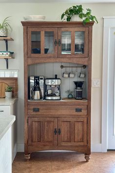 a wooden cabinet with glass doors and shelves on the top is filled with coffee equipment