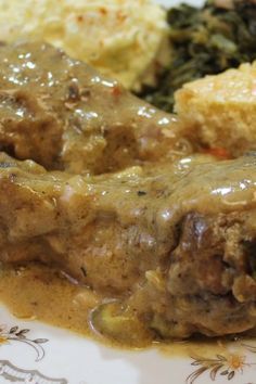 meat and gravy on a plate with mashed potatoes, spinach and broccoli