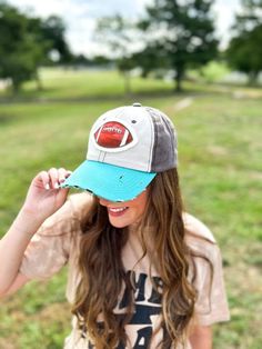 a girl wearing a hat with a red and blue patch on the front, standing in a field