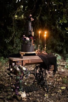 a table topped with a black cake and two candles