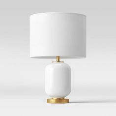 a white table lamp with a gold base and a white lampshade on top