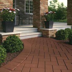 a brick walkway with potted plants on the side