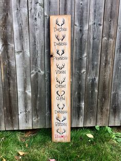 a wooden sign with some writing on it in front of a wood fence and grass