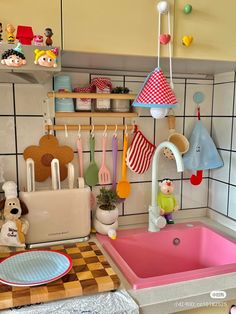 a toy kitchen with toys on the counter and utensils hanging from the wall