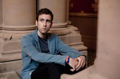 a man is sitting on the ground in front of some pillars and looking at the camera