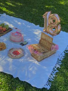 a picnic blanket on the grass with cake and other food items laid out on it