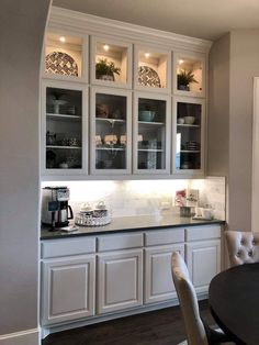 a kitchen with white cabinets and black counter tops, along with a dining room table