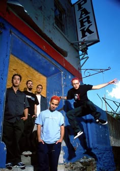 a group of young men standing next to each other in front of a blue building