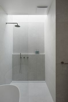 a bathroom with a walk in shower next to a white bathtub and toilet paper dispenser