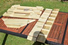 a table made out of wooden planks on top of green grass with scissors in the middle