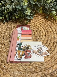 an open book sitting on top of a wicker basket next to some plants and books