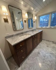 a large bathroom with marble counter tops and double sinks in front of two mirrors on the wall