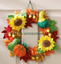 a wreath with sunflowers and pumpkins hanging on a door