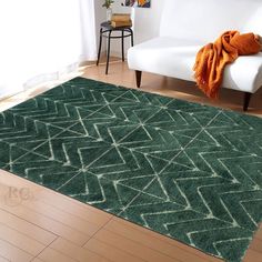 a living room with a white couch and green rugs on the wooden flooring