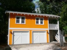 a two car garage with an attached porch and stairs to the second floor is painted yellow