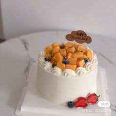 a white cake topped with fruit on top of a table