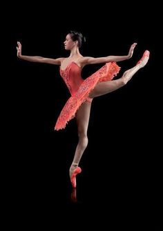 a woman in a red leotard and pink ballet shoes is dancing with her legs spread out