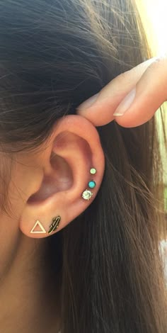 a woman's ear has three different colored stones on it and is wearing an ear cuff