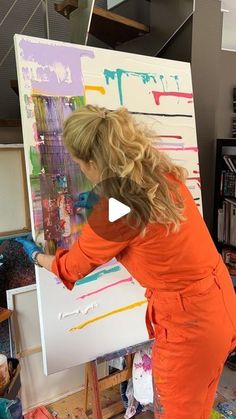 a woman in an orange jumpsuit painting on canvas