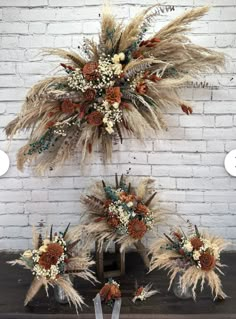 dried flowers and feathers are arranged in front of a brick wall