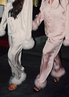 two women dressed in pink and white posing for the camera with one holding her hand