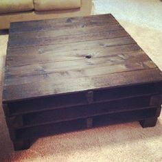 a wooden coffee table sitting on top of a carpeted floor