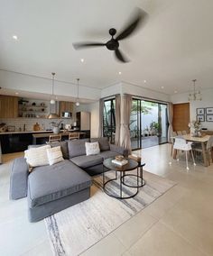 a living room filled with furniture and a ceiling fan in the middle of an open floor plan