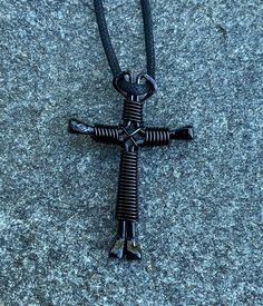 a black cross pendant is laying on the ground