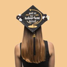 a woman with long hair wearing a graduation cap that says and so the adventure begins