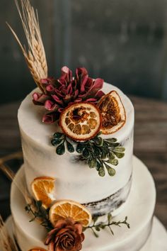 a white cake with orange slices and dried flowers