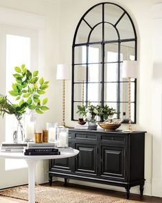 a room with a table, mirror and plants