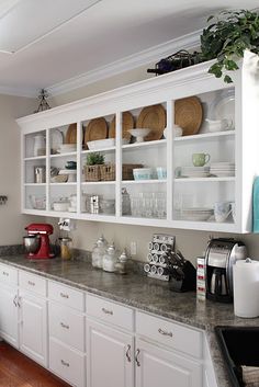 a kitchen filled with lots of white cupboards and counter top space next to a wooden floor